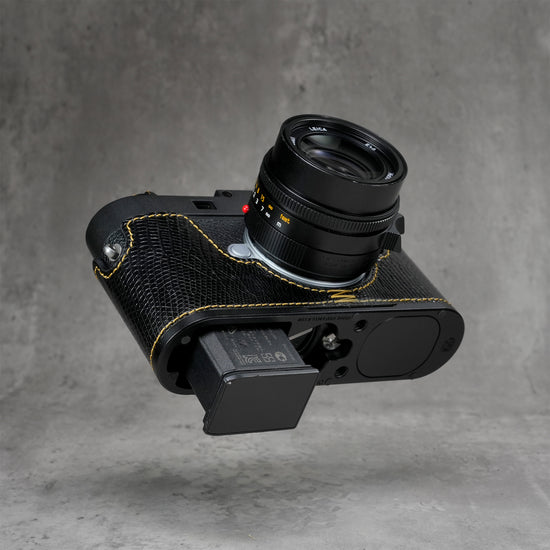 Battery released from a Leica M11 with the black gloss lizard FlexCase still fitted