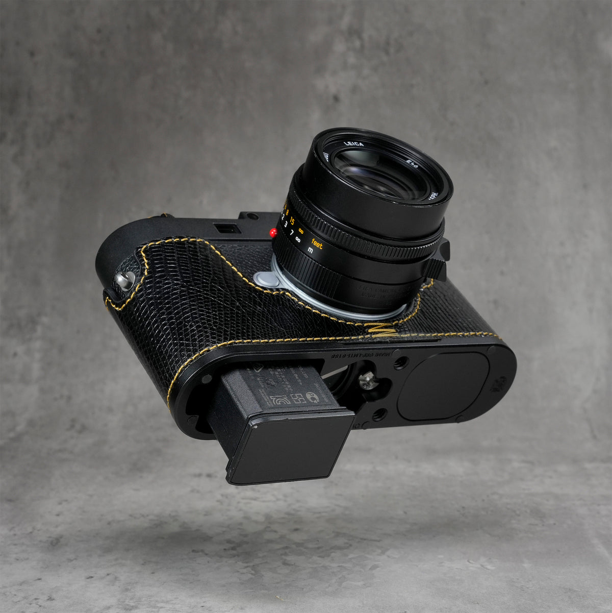 Battery released from a Leica M11 with the black gloss lizard FlexCase still fitted
