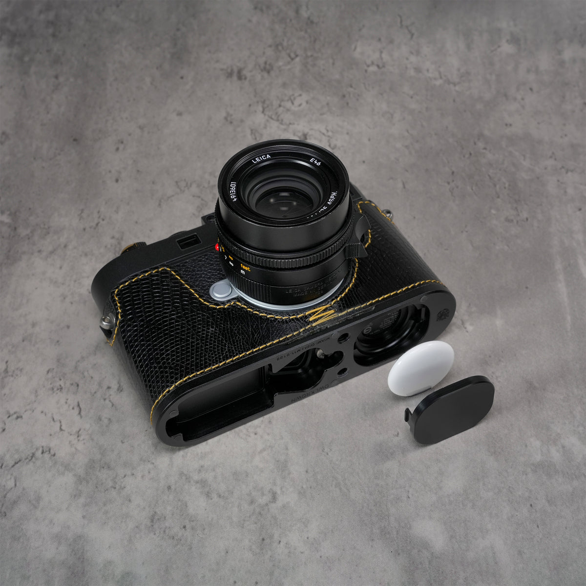 Black gloss lizard FlexCase on a Leica M11 with the AirTag bay open beside the base plate
