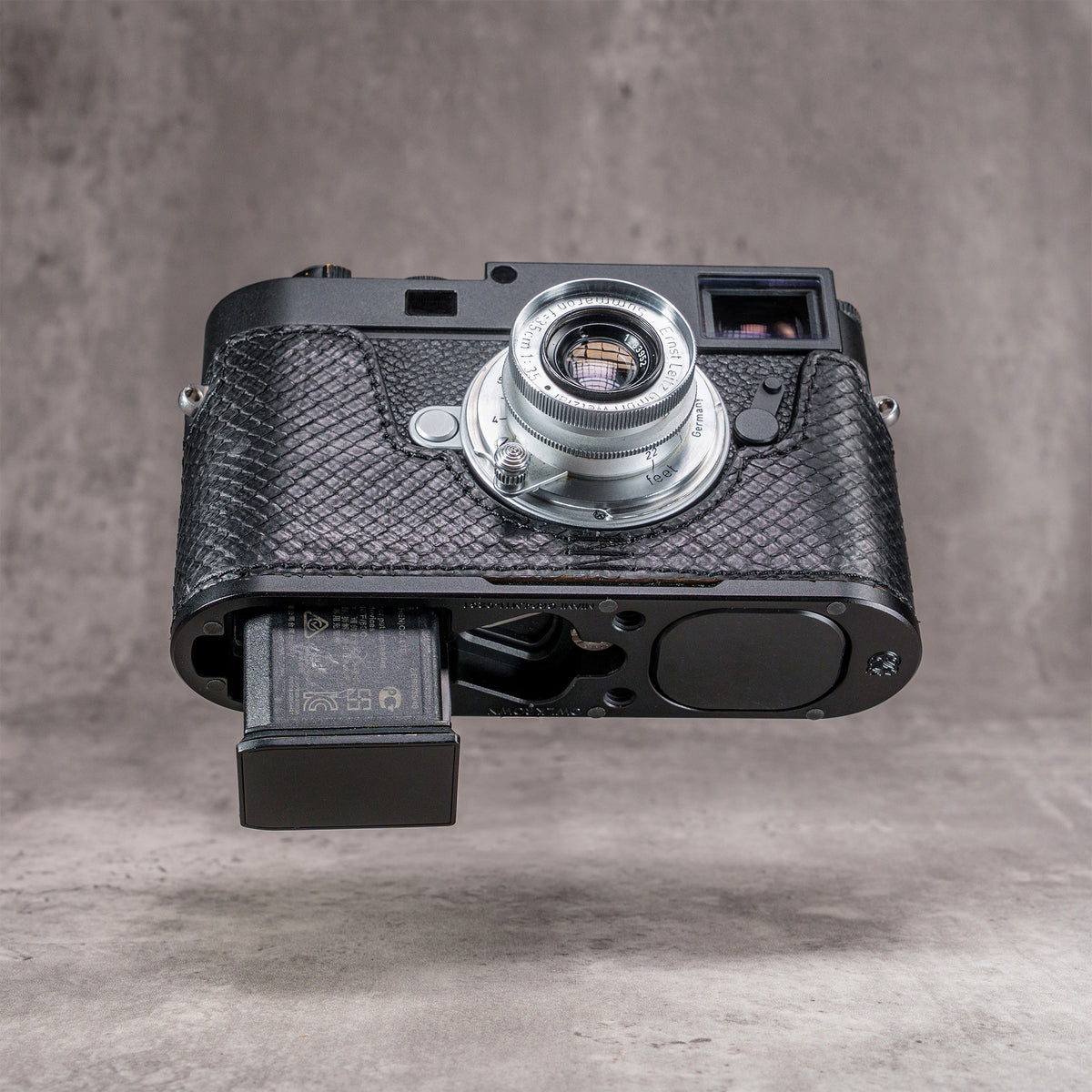 Battery released from a Leica M11 with the black python FlexCase still fitted
