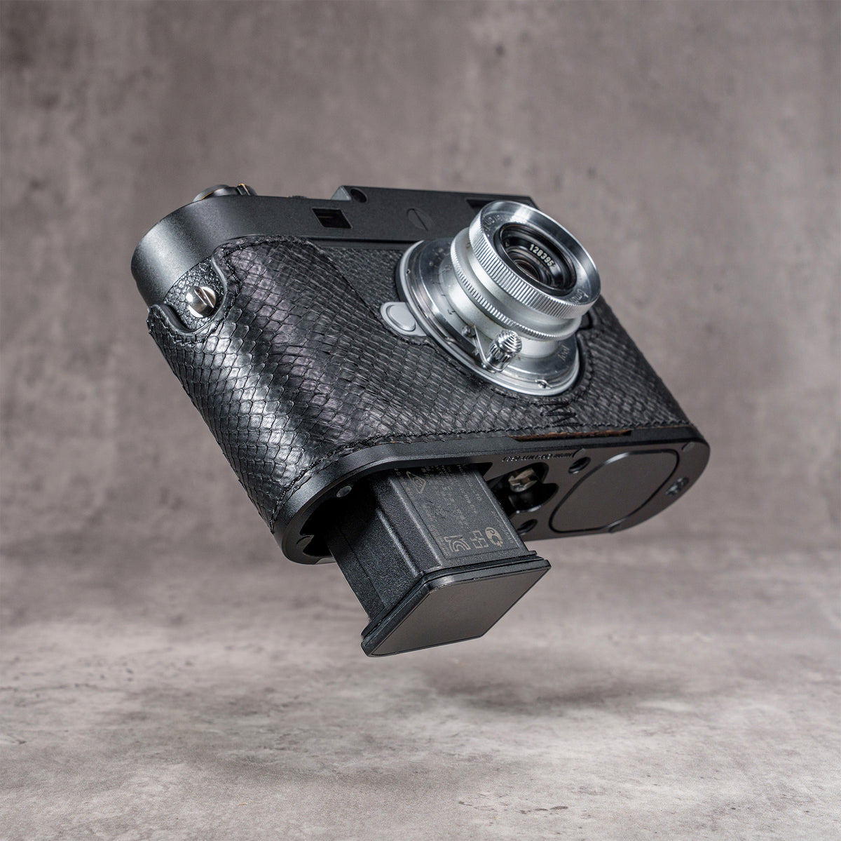 Battery dropping clear of the base plate with the black python FlexCase still on the camera