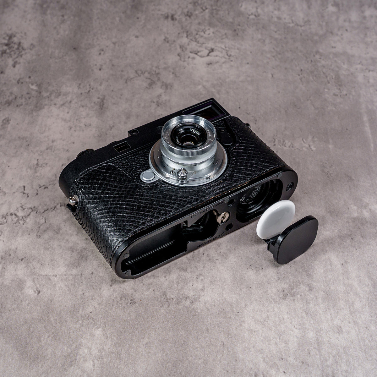 AirTag and its cover cap beside the bay machined into the black python FlexCase base plate