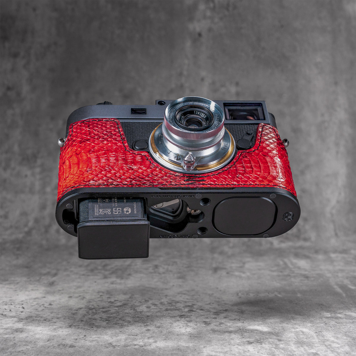 Battery released from a Leica M11 with the red python FlexCase still fitted