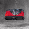 Leica M11 in a red python FlexCase seen from below, Black Chrome base plate and AirTag bay showing