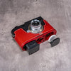 AirTag and its cover cap beside the bay machined into the OxBlood base plate, with the battery released from the Leica M11