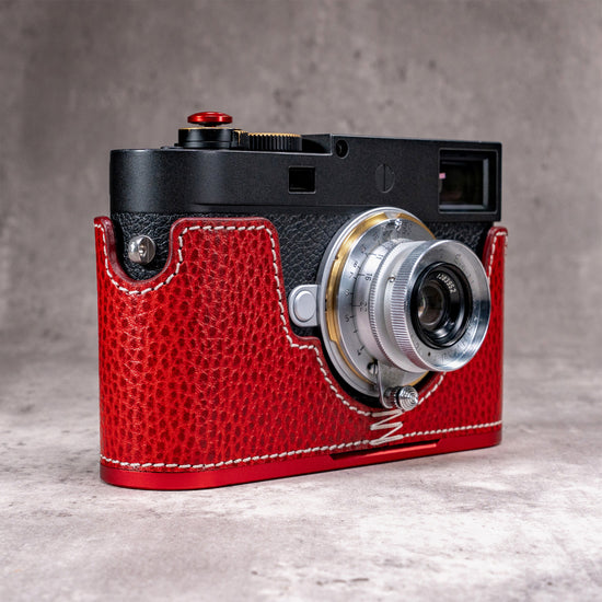 Leica M11 in a Ruby Gloss FlexCase with an OxBlood plate, three quarter front view on a grey studio backdrop