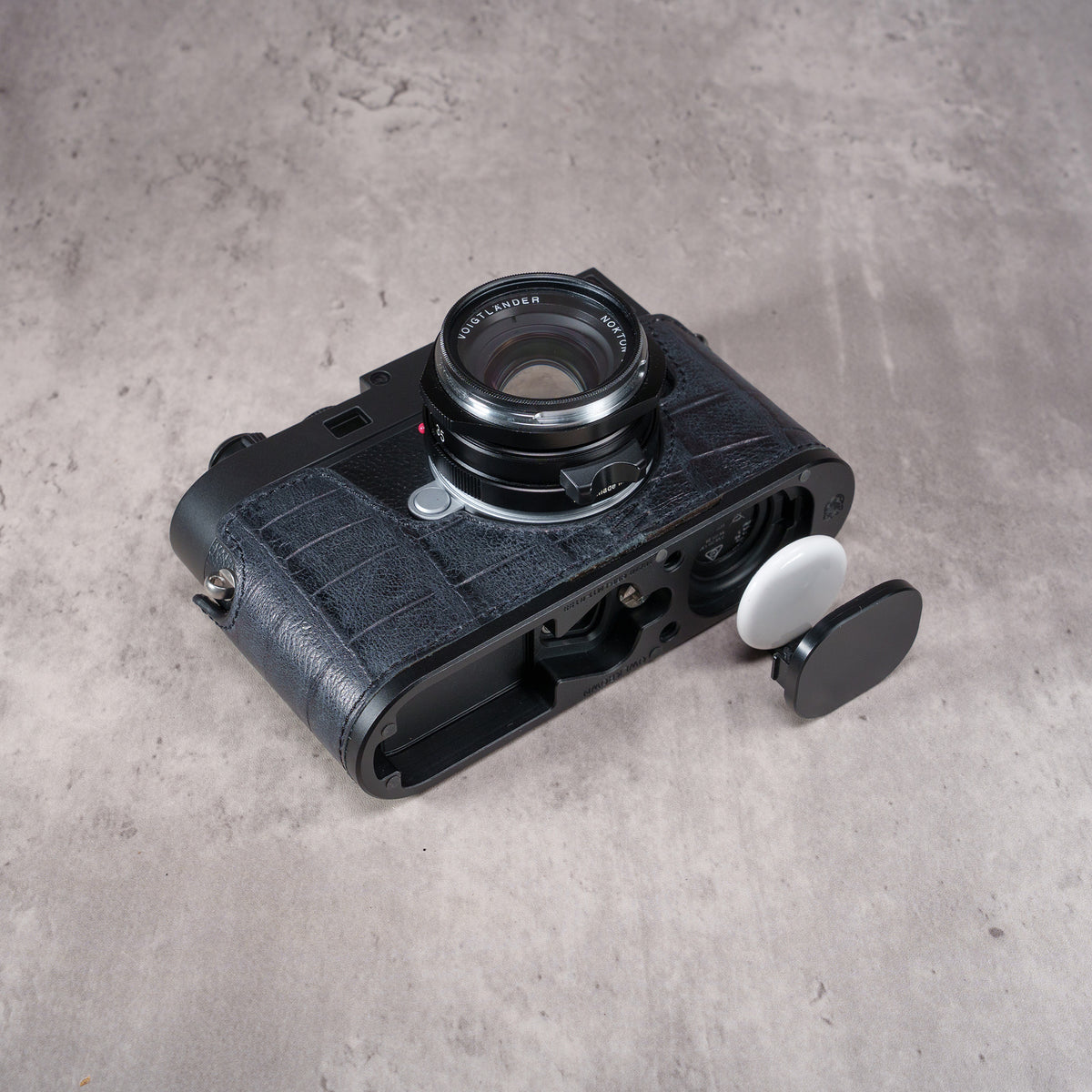 AirTag and its cover beside the open AirTag bay in the Black Swamp FlexCase base plate