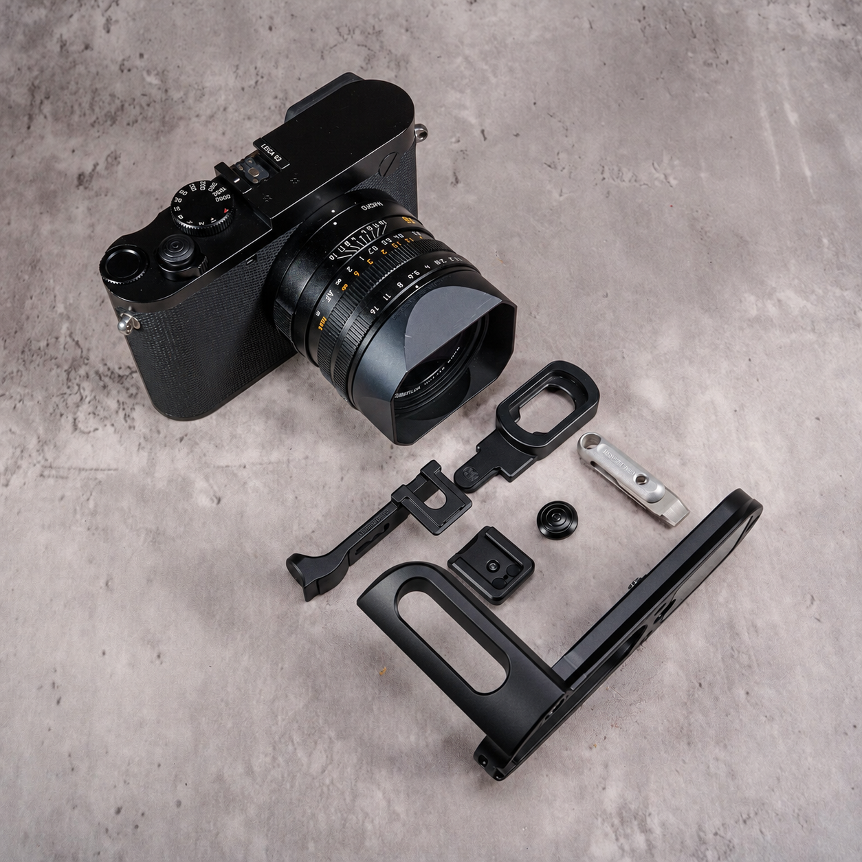 Owlkrown M.O.A.K. kit in aluminum Black Chrome, components laid out beside a Leica Q3