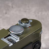 Owlkrown Shutter Topper in Safari anodized aluminum, 12 mm, fitted to an olive Leica M shutter button