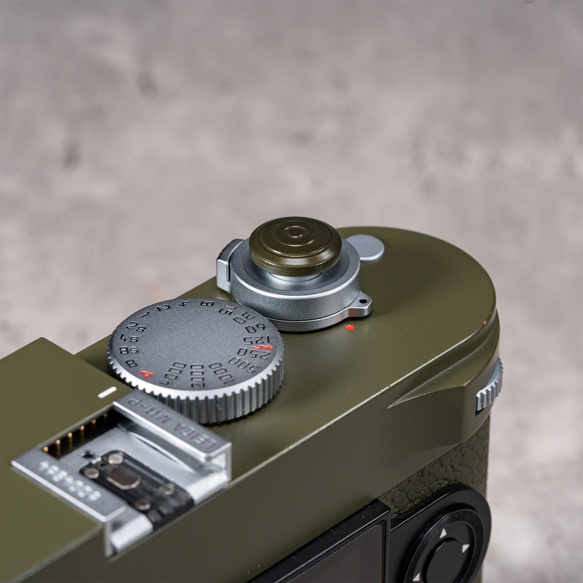 Owlkrown Shutter Topper in Safari anodized aluminum, 12 mm, fitted to an olive Leica M shutter button