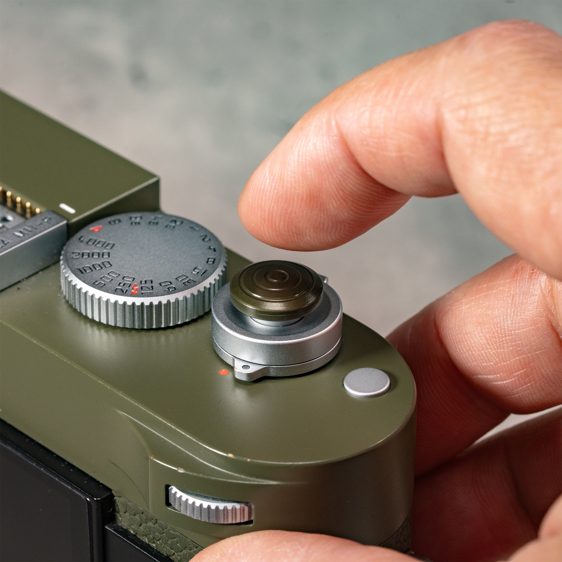 A finger resting on the Safari Shutter Topper, showing the added grip and shutter feel