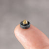 Black Cerakote Shutter Topper balanced on a fingertip, showing its 7.25 mm scale and brass thread