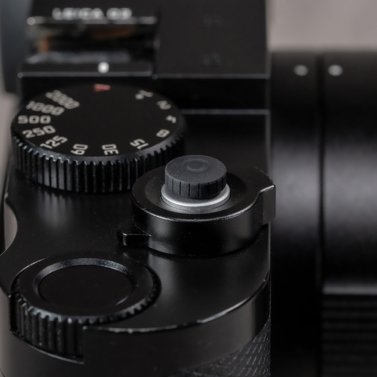 Black Cerakote Shutter Topper on a black Leica M top plate with shutter speed dial and lens in frame