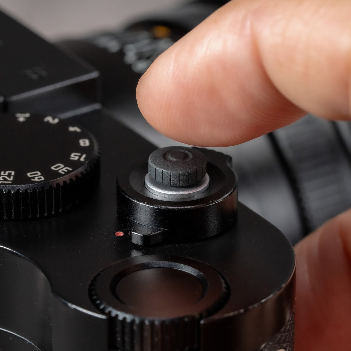 Photographer pressing the Black Cerakote Shutter Topper fitted to a black Leica M camera
