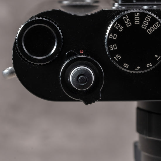 Overhead view of a Leica M top plate with the Black Cerakote Shutter Topper beside the shutter speed dial