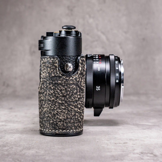 A Leica M11 in the Buffalo SlimCase seen from the side with the lens beside it