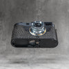A Leica M11 in the Buffalo SlimCase tilted to show the base, with the battery door open