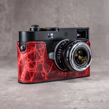 A Leica M11 in the Hot Lava SlimCase, three quarter front view with the lens attached