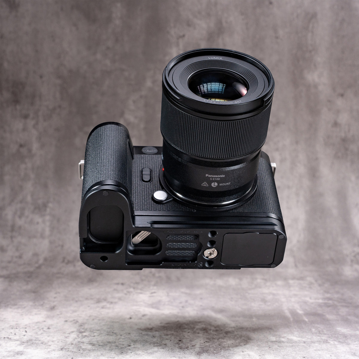 Leica SL3 and lens seen from below, showing the Owlkrown FlexPlate base and its 1/4-20 mounting points