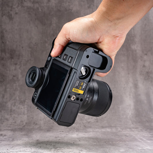 Leica SL3 held in one hand with the Owlkrown FlexPlate fitted, rear screen and card bay in view