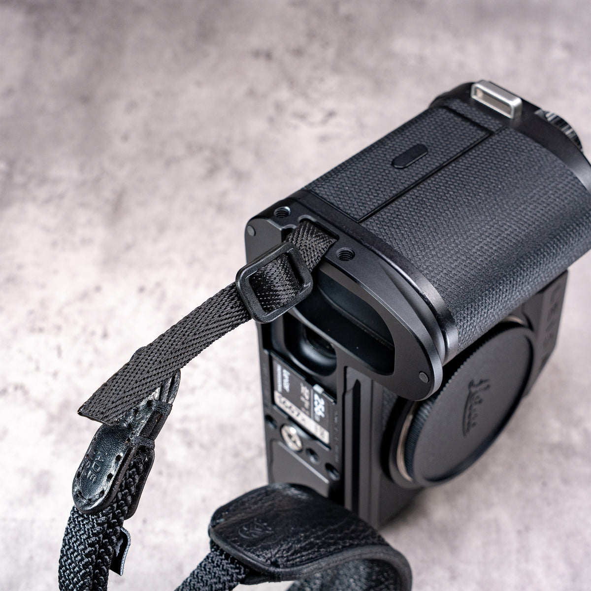 Owlkrown FlexPlate for Leica SL3 seen from above, with a strap looped through the side lug
