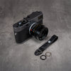 Leather Thumb Strap - Stealth beside a Leica M camera with black and polished split rings