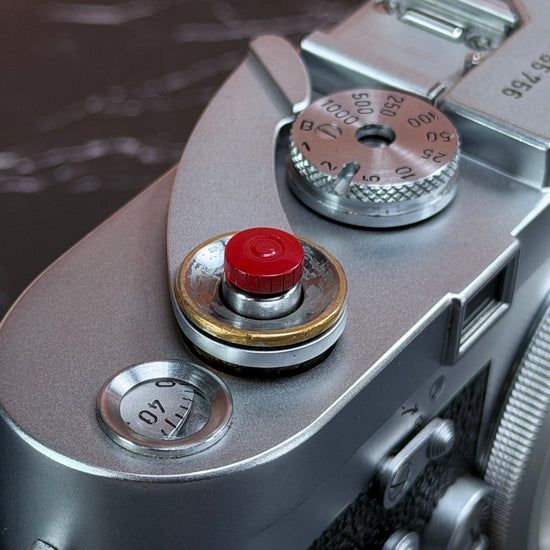 Close view of the Red Cerakote Shutter Topper seated in a Leica M3 shutter button