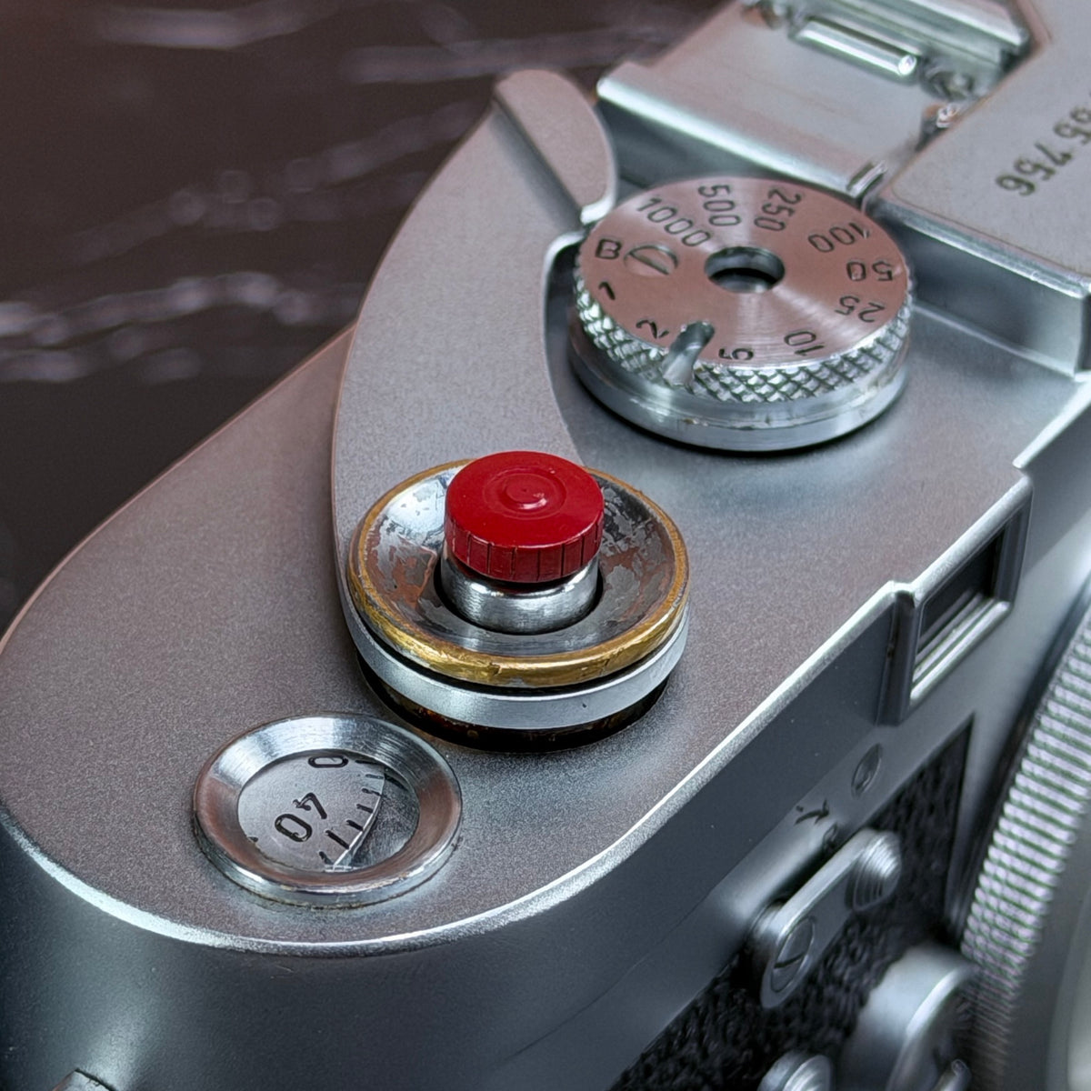 Close view of the Red Cerakote Shutter Topper seated in a Leica M3 shutter button